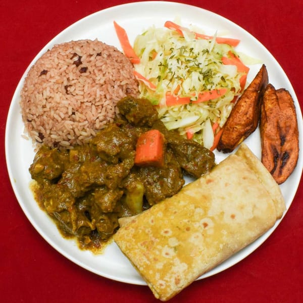 A Caribbean Delight meal with curry goat, rice and peas, cabbage, plantains, and roti.