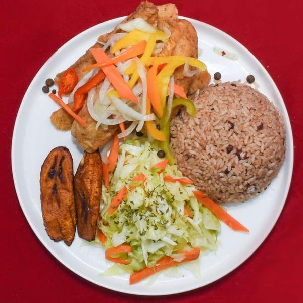 Caribbean Delight's fried chicken with rice and peas, plantains, and cabbage on a white plate.