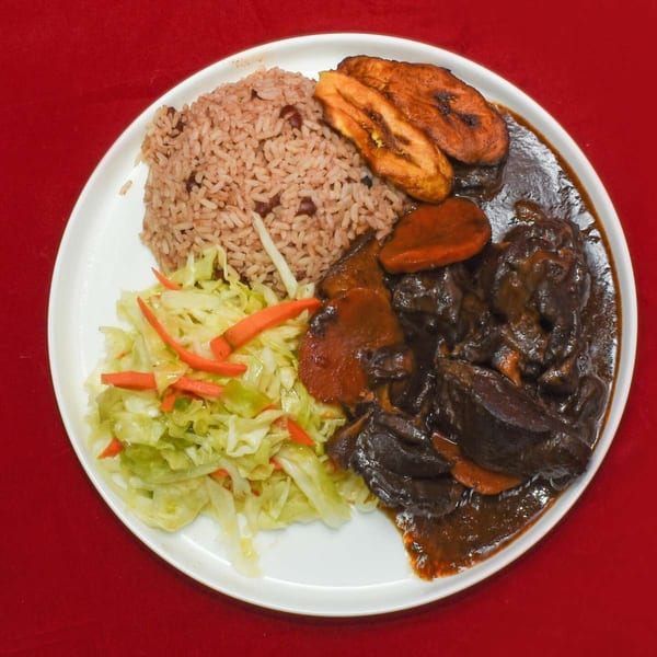 A Caribbean Delight plate with rice and peas, stewed meat, fried plantains, and sautéed cabbage.