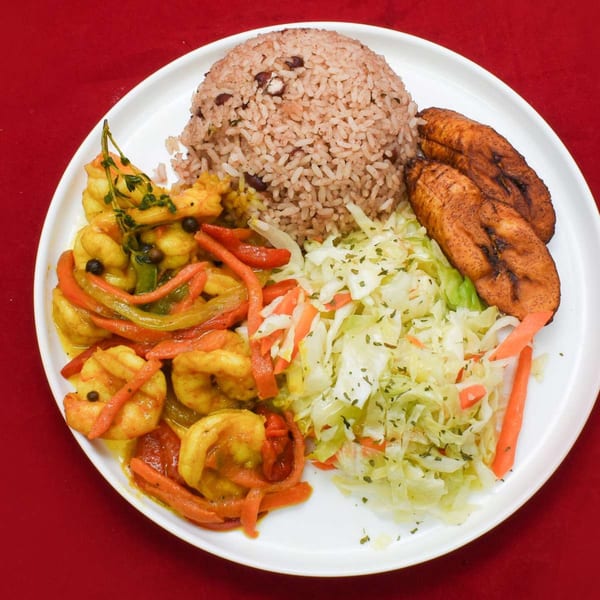 Caribbean Delight's curry shrimp with rice and peas, fried plantains, and cabbage on a white plate.